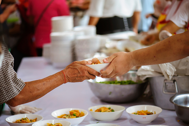 manos sirviendo comida a otras manos en comedor social