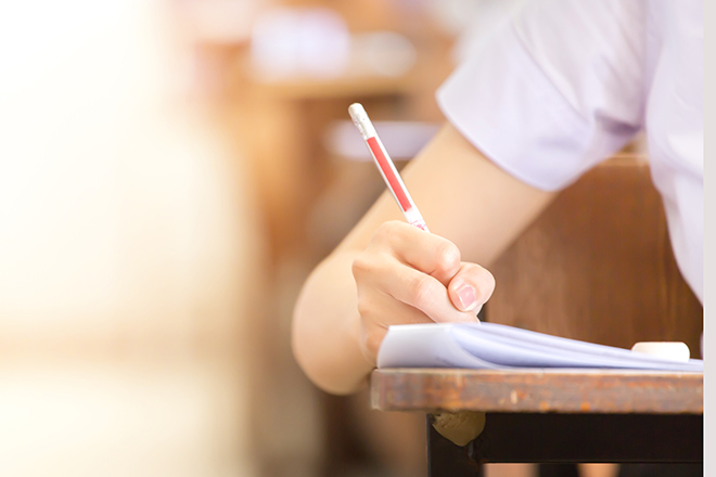 Detalle del brazo y mano de una persona escribiendo con un lápiz en un examen