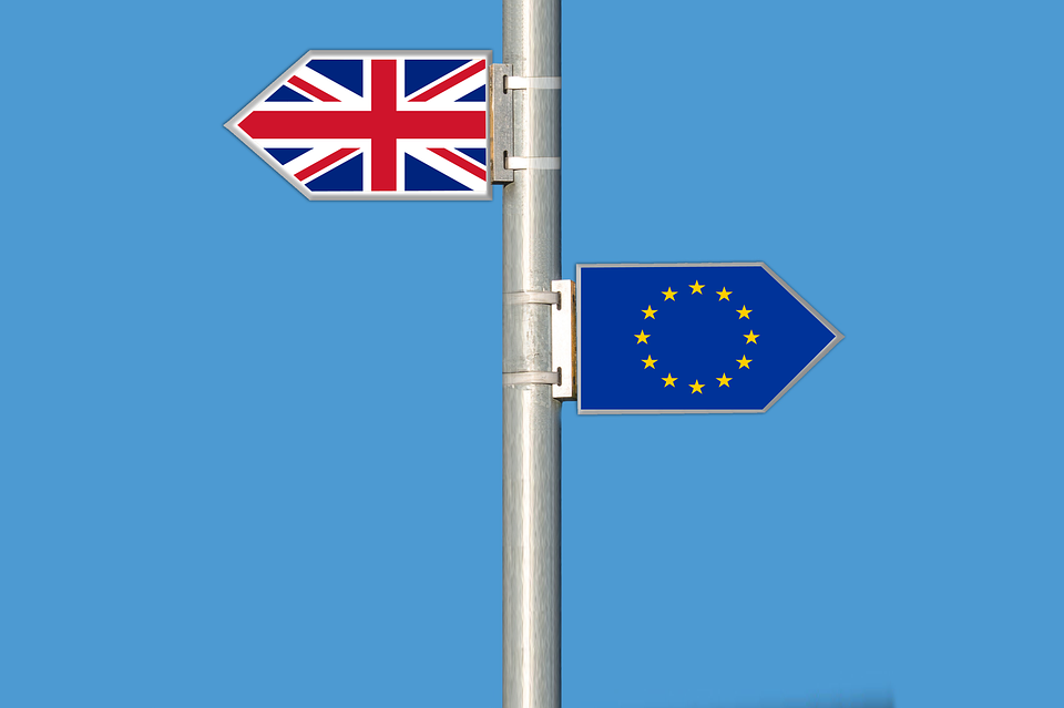 Poste con una bandera de Reino Unido y otra de la UE apuntando en direcciones opuestas
