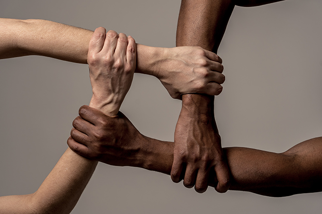 Brazos de raza blanca y negra con manos entrelazadas