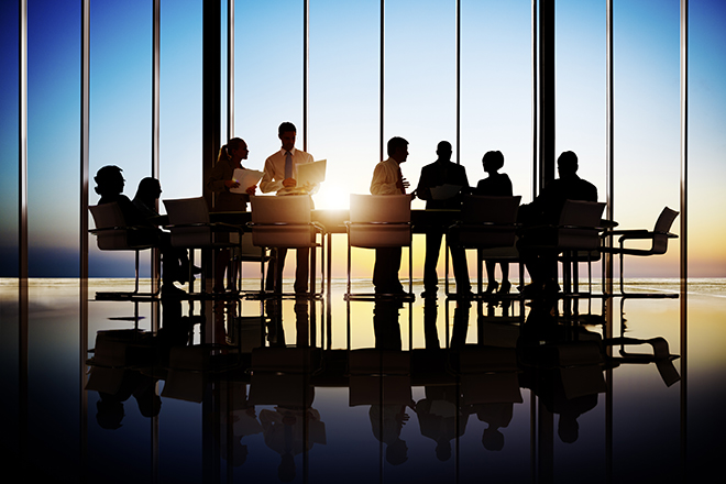 Grupo de personas reunidas alrededor de una gran mesa de oficina