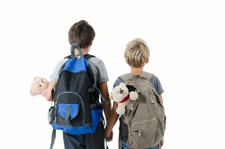 Dos niños de espaldas con mochilas van de la mano
