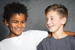 Dos niños cogidos por el hombro sonriendo