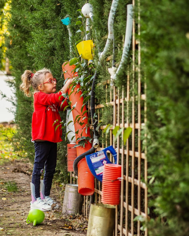 Niña en un jardín utilizando contenedores reciclados para regar