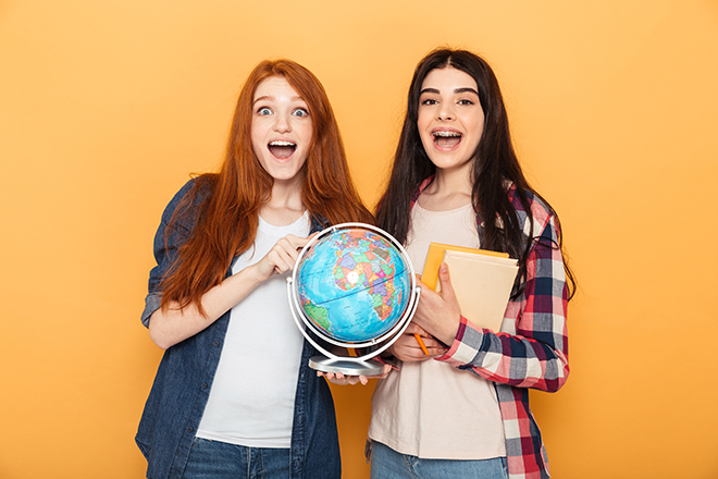 Dos chicas jóvenes sosteniendo un globo terráqueo