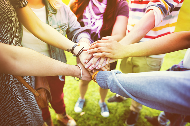Un grupo de jóvenes enlazan sus manos formando un círculo