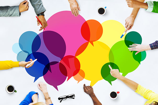 Manos de jóvenes formando un círculo sobre un grupo de pictogramas multicolor de preguntas