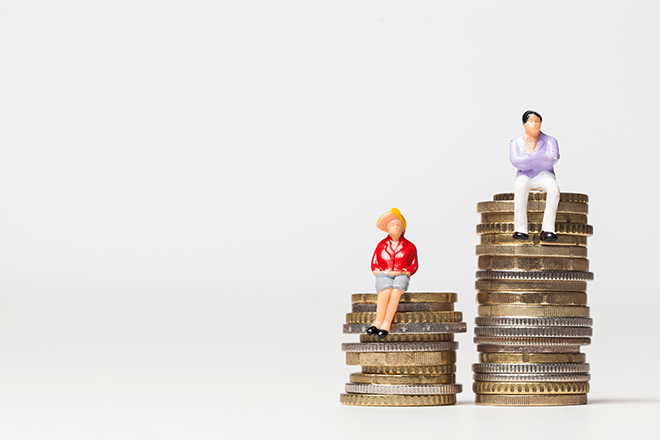 Figura de una mujer sentada sobre una pila de monedas de euros y figura de un hombre sentado sobre otra pila de monedas de euros más alta