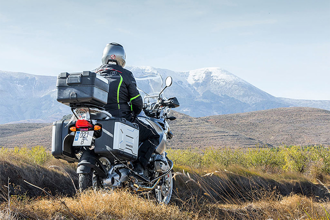 Hombre de espaldas montado en una moto, parado, mirando un paisaje aragonés
