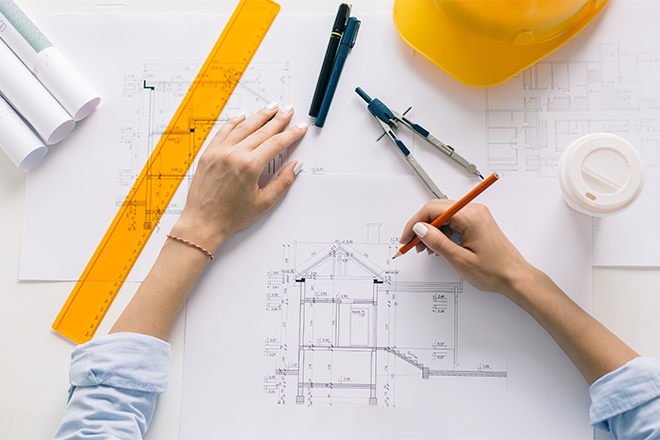 Manos de una mujer arquitecta dibujando en un plano arquitectónico