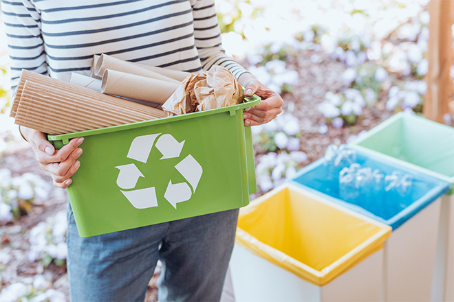 Mujer sujetando una caja verde con el símbolo del reciclaje