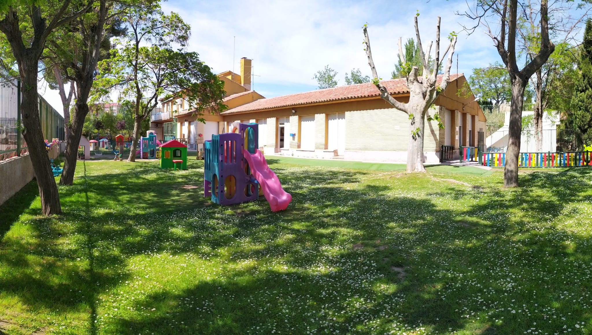 Exterior de la guardería infantil con césped y toboganes infantiles