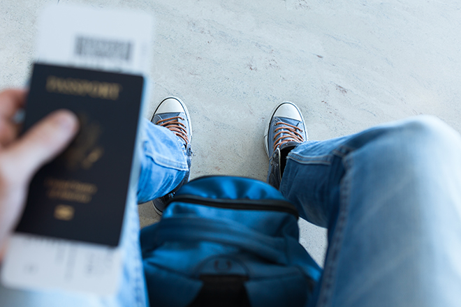 Zapatillas de un joven sentado observando su pasaporte