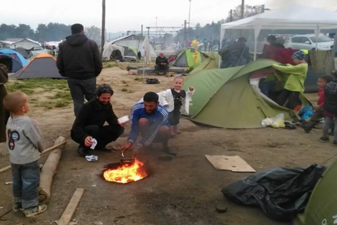 Grupo de personas en un campo de refugiados alrededor de un fuego