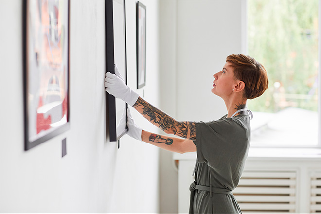 Mujer colgando cuadro en sala de exposiciones