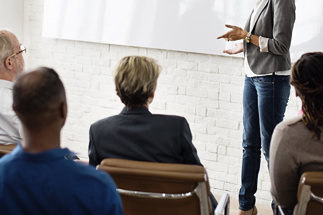 Personas adultas en un aula de formación con una profesora delante