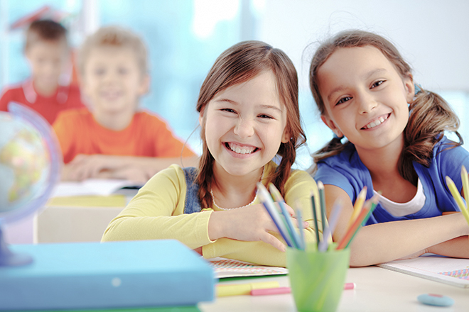 Dos niñas sonrientes sentadas en una clase de primaria