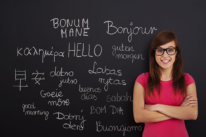 Alumna delante de pizarra con palabras en distintos idiomas 