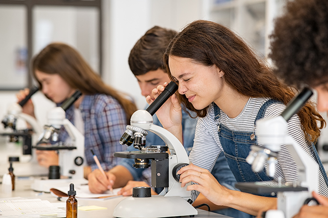 Jóvenes en aula con microscopio