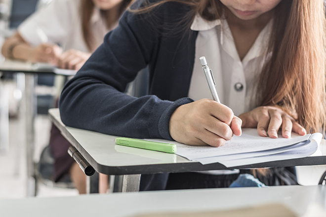 Estudiante escribiendo en un pupitre en clase