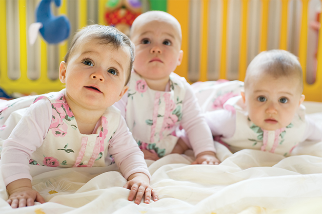 Tres niñas de unos 4 meses boca abajo y mirando hacia arriba