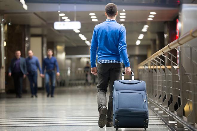 Chico joven arrastra una maleta por una terminal de un aeropuerto.