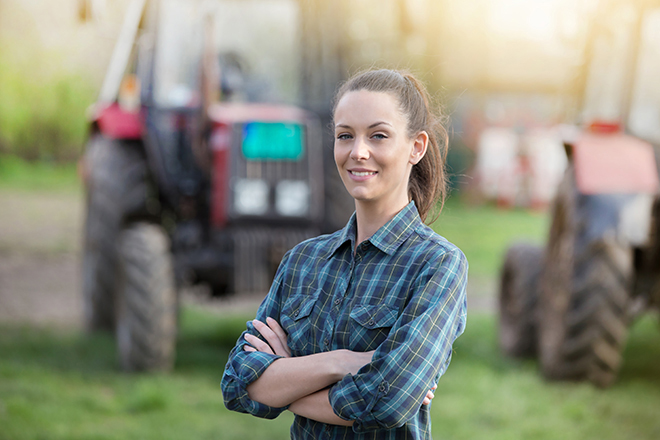 Mujer en medio rural con tractor al fondo