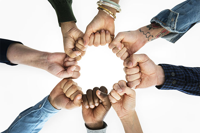 Manos de jóvenes formando un círculo sobre un grupo de pictogramas multicolor de preguntas