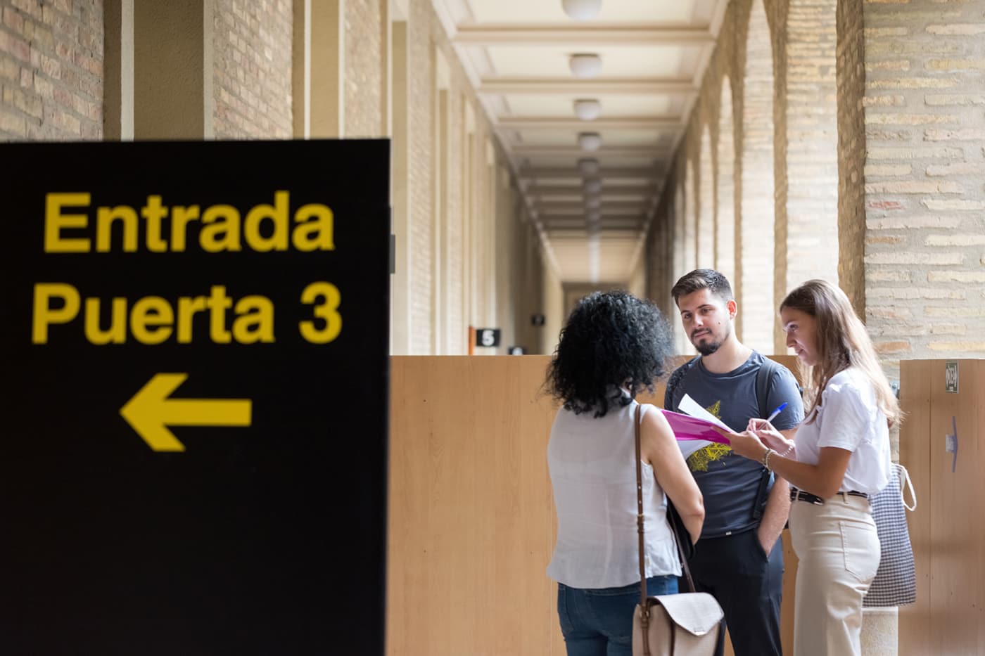 Dos diseñadores a usuarias de Atención a la Ciudadanía en la puerta de una oficina del Gobierno de Aragón