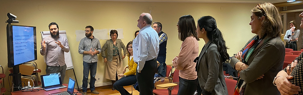 Varias personas reunidas en un aula, mirando a una presentación en una pantalla