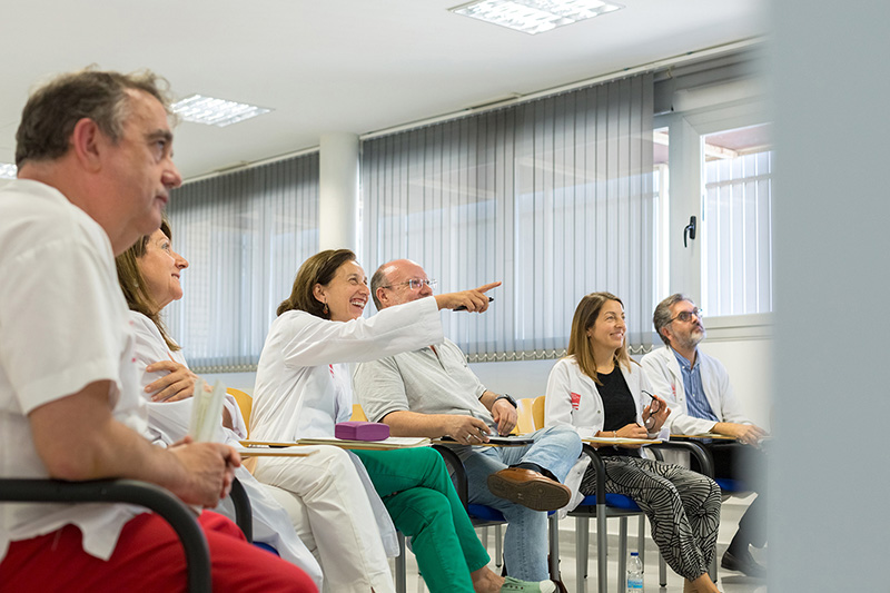 Varias personas, hombres y mujeres con batas blancas en una reunión