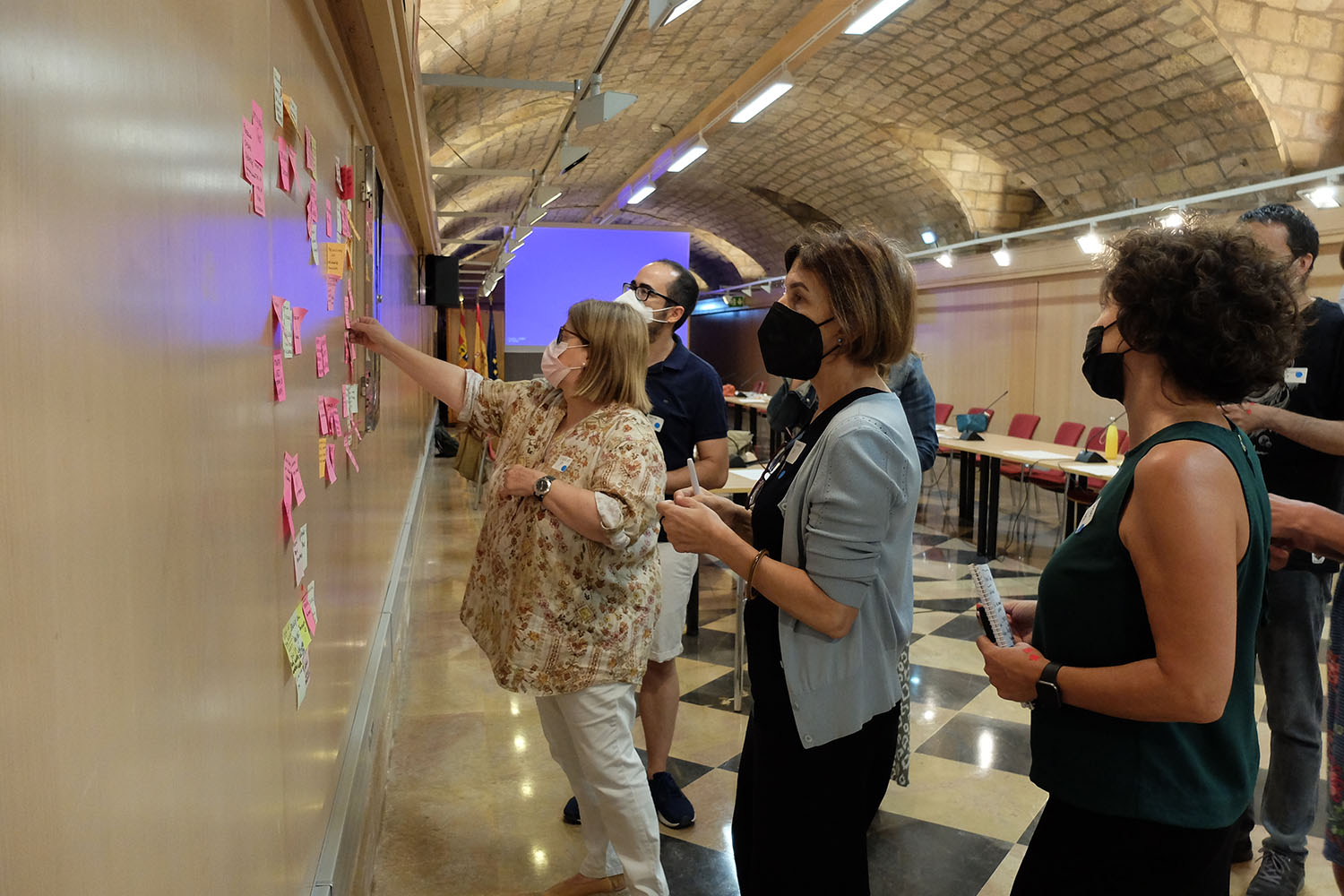 Varias personas organizan notas adhesivas sobre una pared